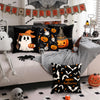 Un juego de fundas decorativas temáticas de Halloween en negro y naranja exhibidas en un sofá con decoraciones estacionales.