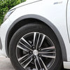Close-up of a white car's wheel arch showing black carbon fiber-look trim and an alloy wheel.