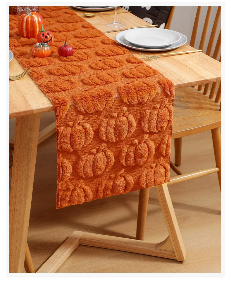 Orange knitted pumpkin pattern table runner laid on a wooden dining table.