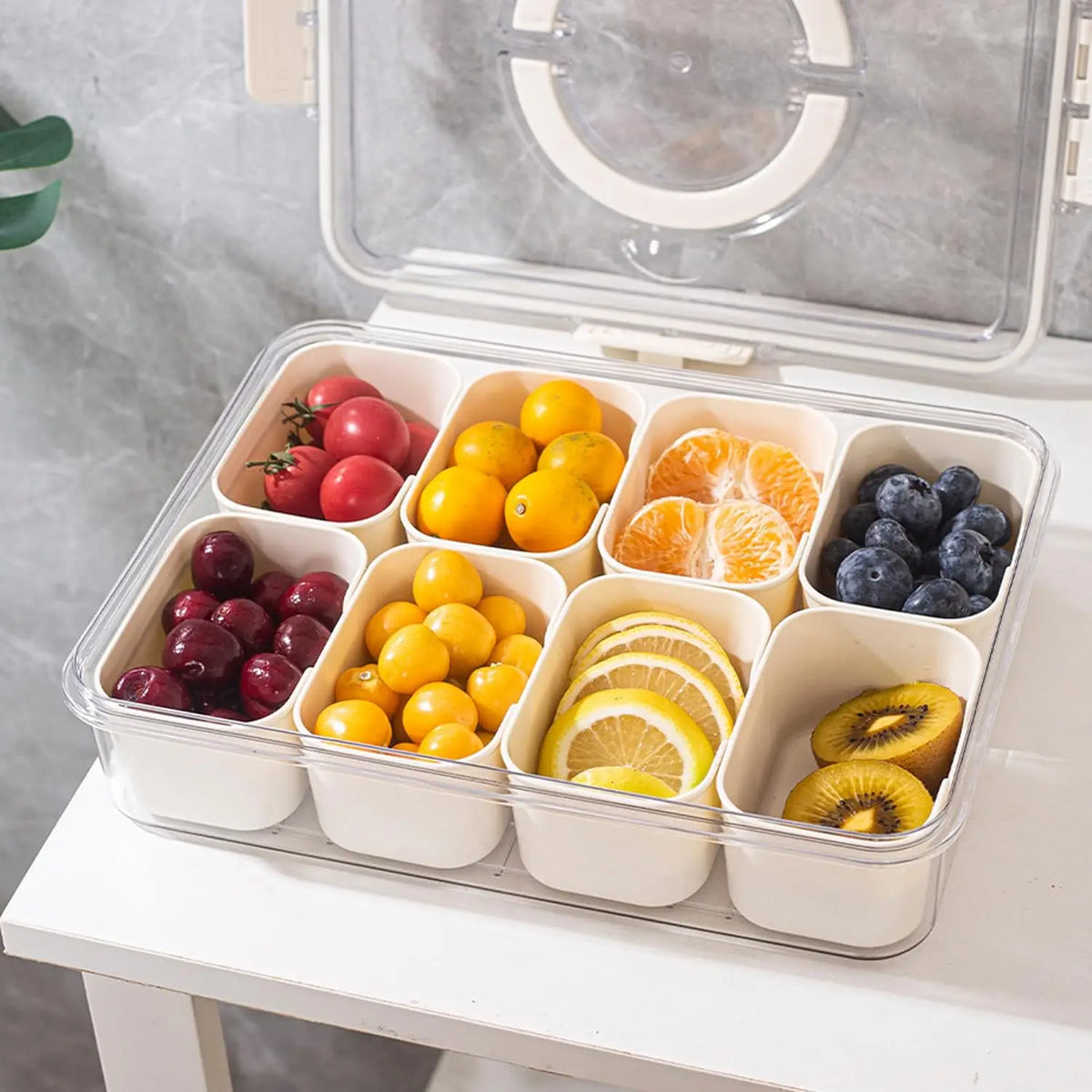 A clear plastic portable snack container with compartments filled with various fruits like apples, plums, oranges, and banana