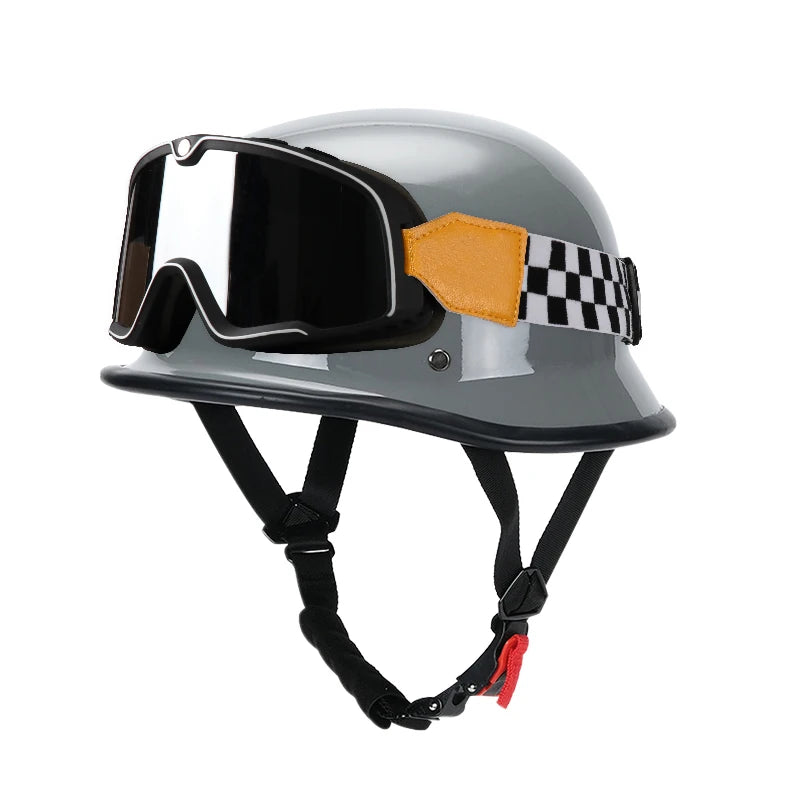 A silver half helmet with an orange and black checkered strap and integrated goggles for motorcycle riding.