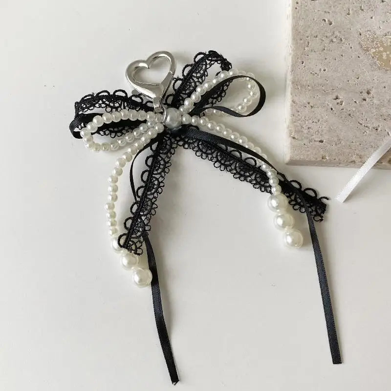 A black lace and pearl bow keychain with a heart charm