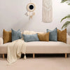 A beige sofa adorned with various textured decorative cushion covers in shades of blue, gold, and cream.