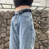 A close-up of a pair of light blue denim jeans with a black elastic belt and a leather buckle, worn by a person.