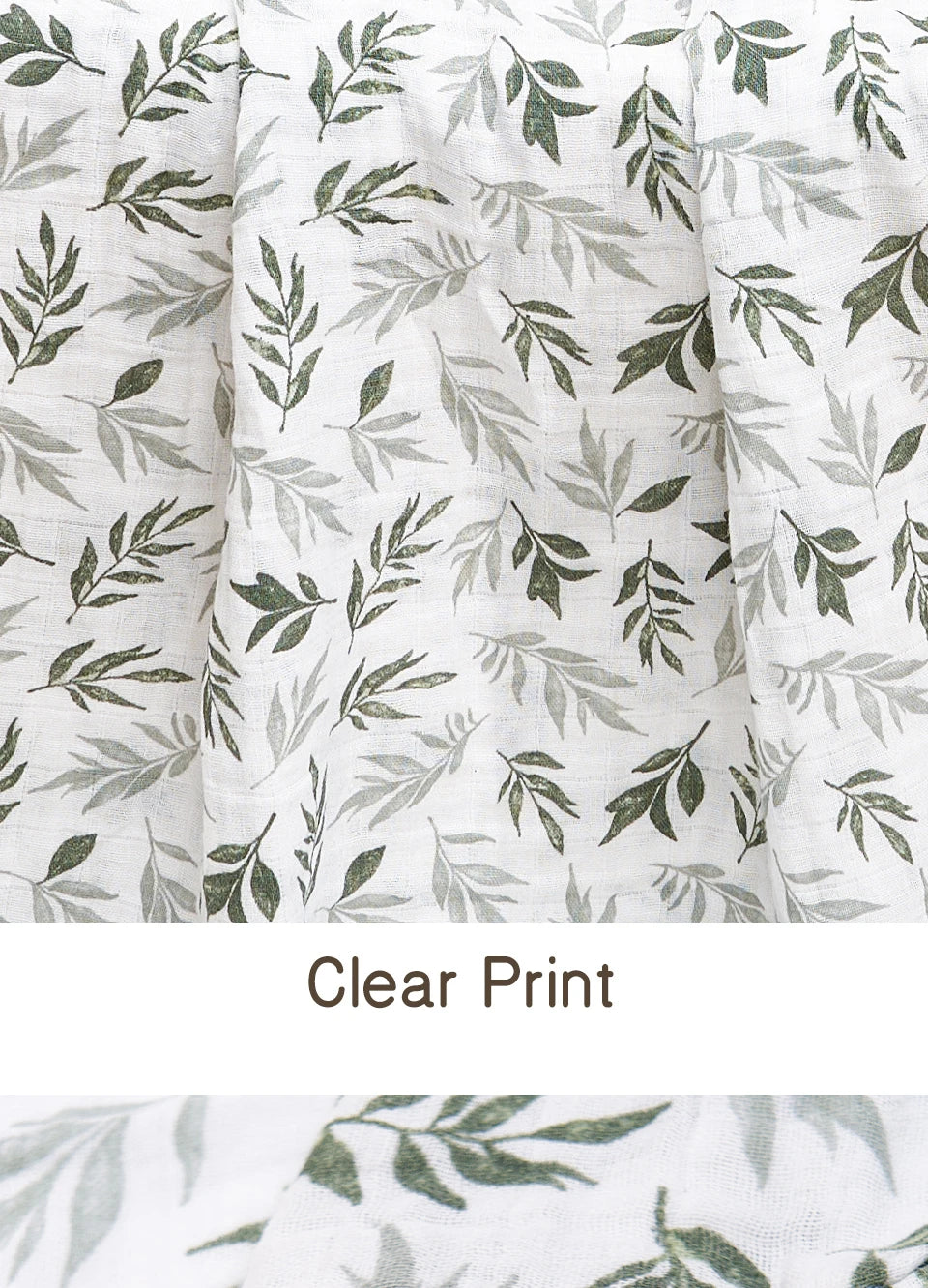 Close-up of a white muslin baby swaddle blanket with a clear green leaf print.