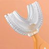 A clear, U-shaped silicone toothbrush for kids is shown attached to an orange handle.