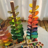 Holzbaumstruktur mit farbenfrohen Blüten und einer Marmorbahn für Musikspielzeug.