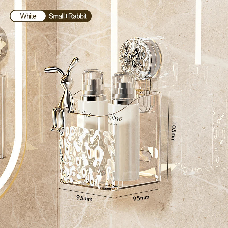 A clear wall-mounted storage basket with a water ripple design holds a silver-colored soap dispenser and a small rabbit figur