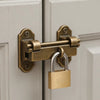 A brass padlock has a key attached, mounted on a white door with a light-colored frame.