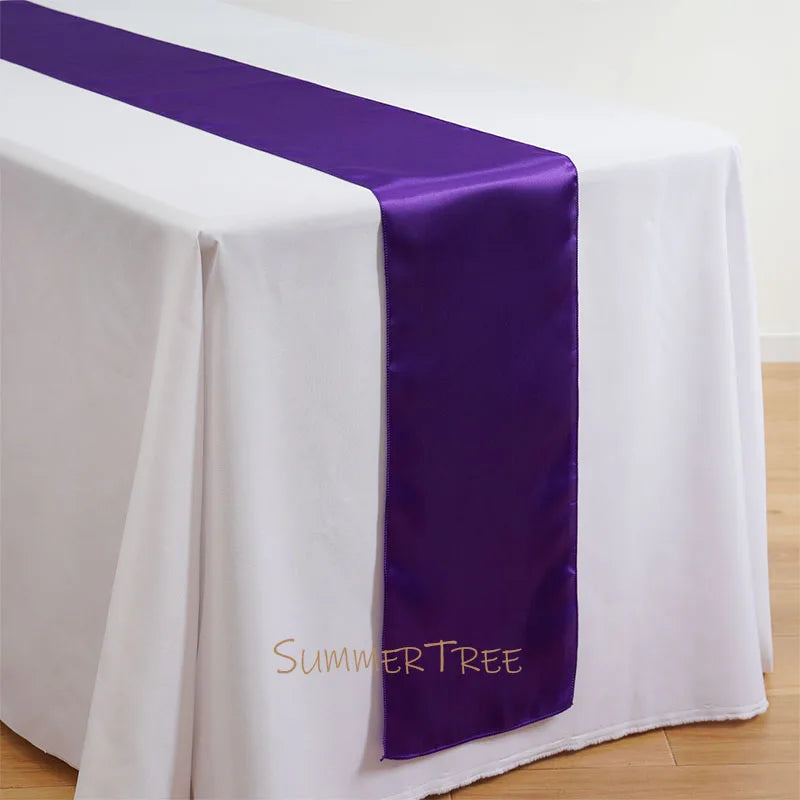 Elegant satin purple table runner draped across a white tablecloth.