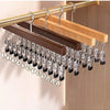 A wooden clip hanger with twelve metal clips is displayed on a light wood panel.