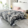 A gray and black gradient bubble fleece throw blanket draped over a white sofa in a bright room.