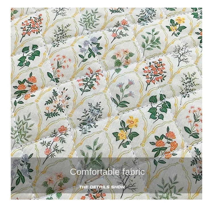 A quilted fabric pattern featuring floral and botanical prints in soft green, orange, and gray tones.