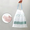 A hand holds a large, white drawstring trash bag with handles, showing a close-up of the plastic material.