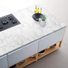 A white marble countertop with a black induction cooktop and storage drawers featuring wooden shelves.