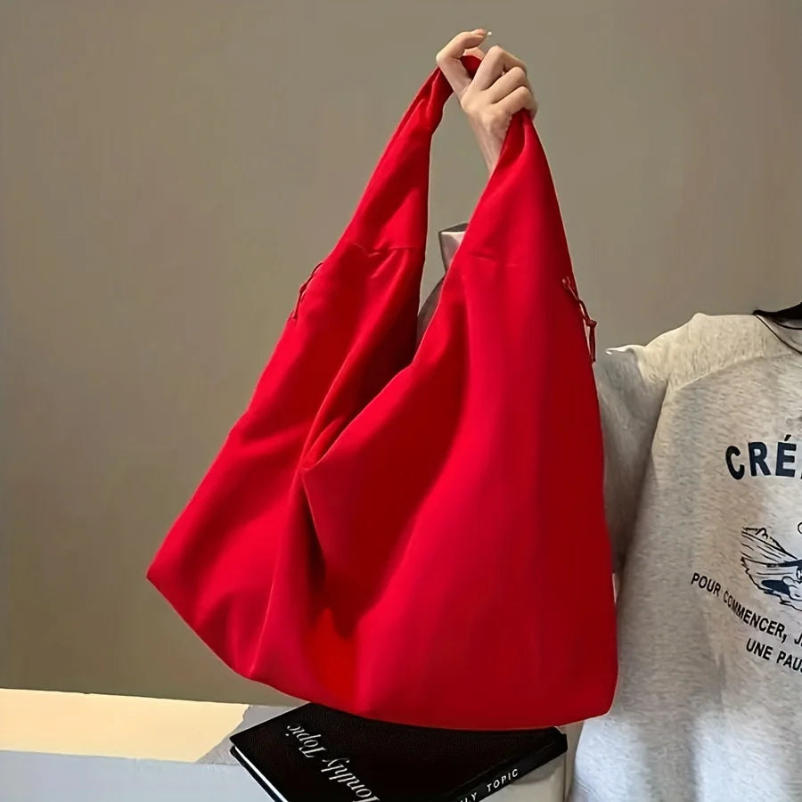 A bright red lightweight nylon tote bag with a secure zipper closure is held up against a light background.