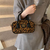 A brown leather retro leopard print hobo satchel bag carried by a person wearing a beige blazer.