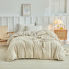 Beige besticktes Blumen-Duvetcover-Set auf einem Bett mit weiß gerahmtem Kopfteil und natürlichem Licht.