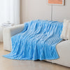 A bright blue soft and cozy brushed flannel throw blanket draped over a light-colored sofa.