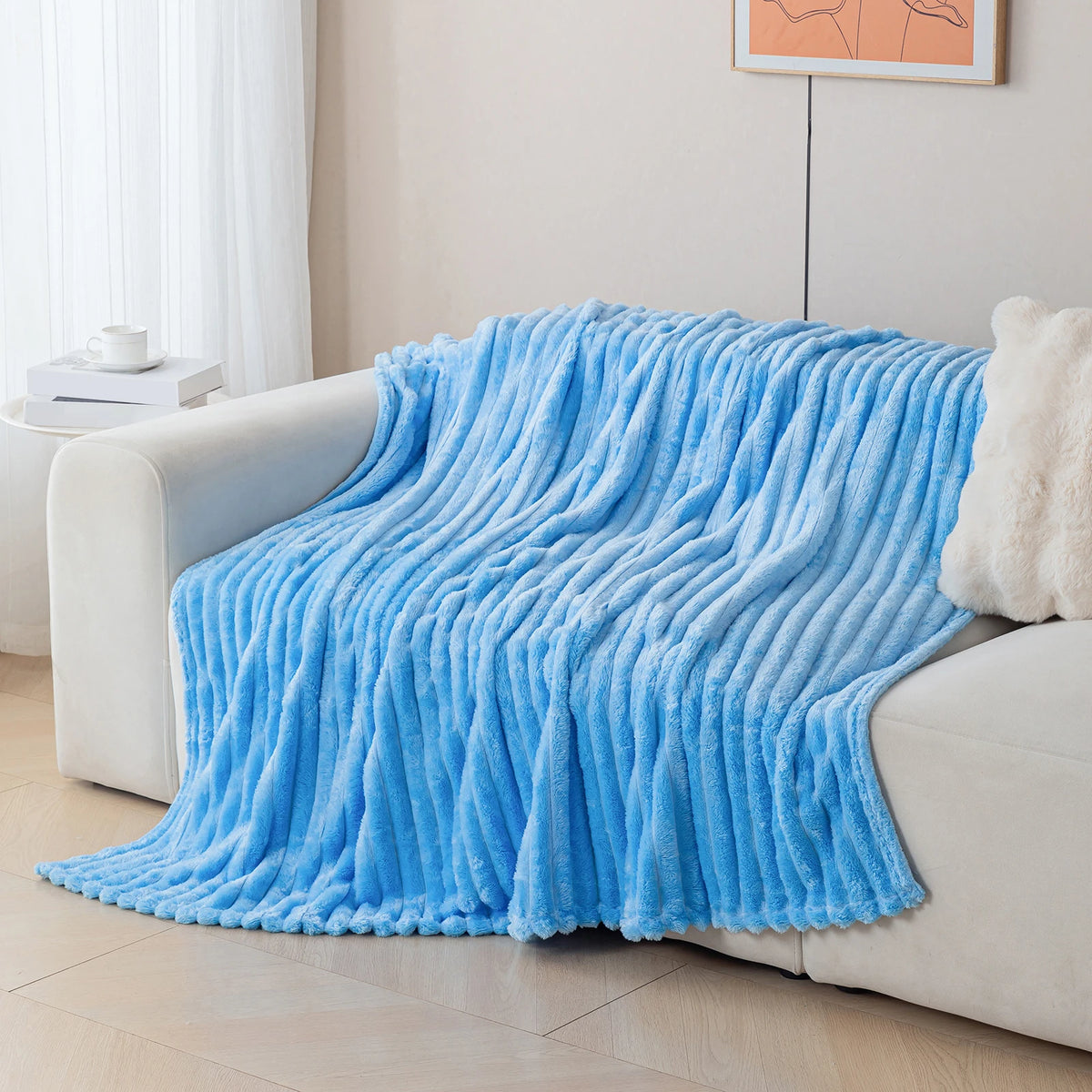 A bright blue soft and cozy brushed flannel throw blanket draped over a light-colored sofa.