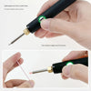A hand holds a black soldering iron with a green light, demonstrating its lightweight design.