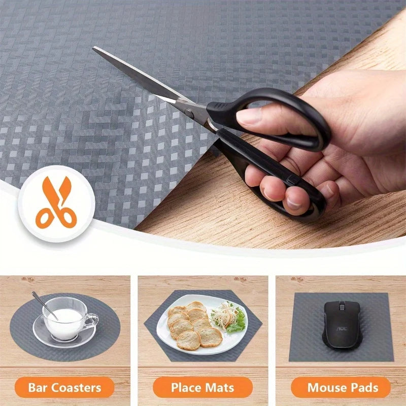 A hand is using a kitchen scissor to cut a piece of dark gray shelf liner or mat.
