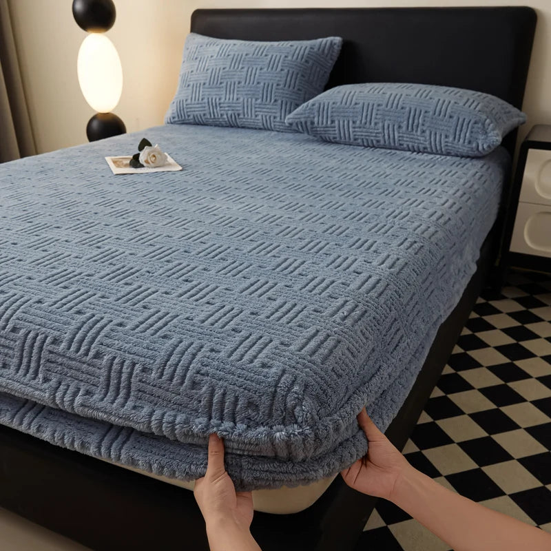 A blue textured mattress cover is shown on a bed, with a hand touching the fabric.