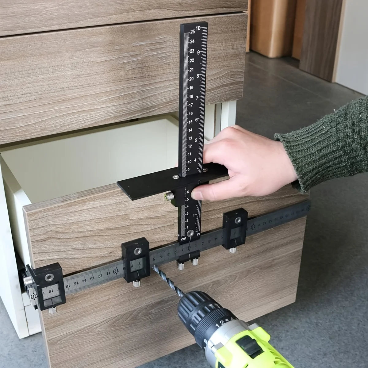 A hand is using a measuring tool to align cabinet hardware for installation.