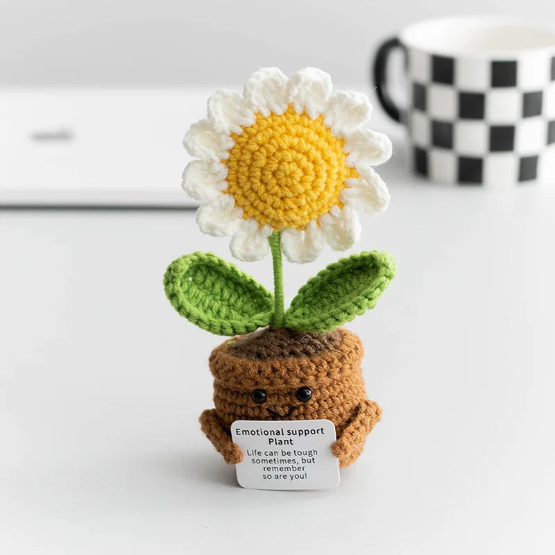 Handmade crochet plant decoration featuring a white and yellow flower on a brown base.