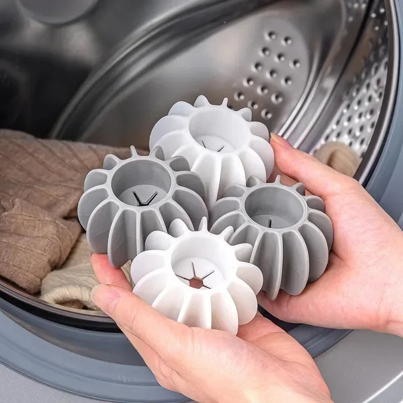 A hand holds several white silicone laundry balls for pet hair and lint removal inside a washing machine drum.