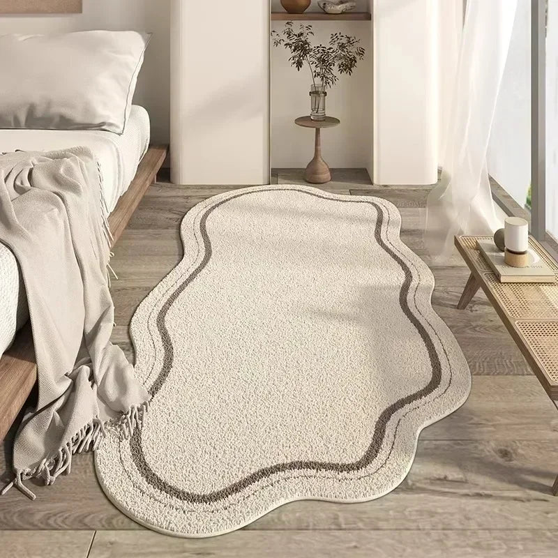 A beige irregular area rug with a plush texture is placed on a light wood floor next to a white wall and shelving.