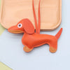 An orange dachshund shaped keychain made of PU leather with long ears and a loop for attachment.