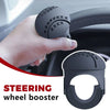 A hand is shown gripping a black steering wheel booster knob designed for one-hand control.