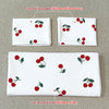 Two pillowcases and one duvet cover in a red cherry print design on a light background