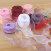 Rolls of satin ribbon in various shades of pink, purple, and beige for gift wrapping and crafts
