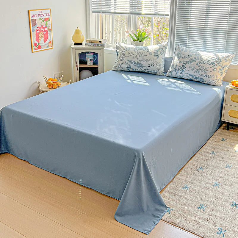 A light blue floral duvet cover set with a matching flat sheet and pillows displayed on a bed.