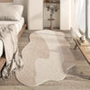 A beige irregular area rug with a plush soft texture placed on a light wood floor in a modern interior.