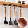A set of wooden and black silicone spatulas hanging from a wooden rack.