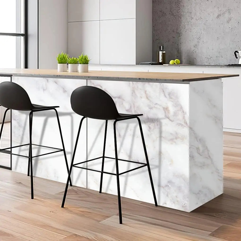 A modern kitchen counter with a white marble top and black bar stools, featuring glossy pink marble contact paper.