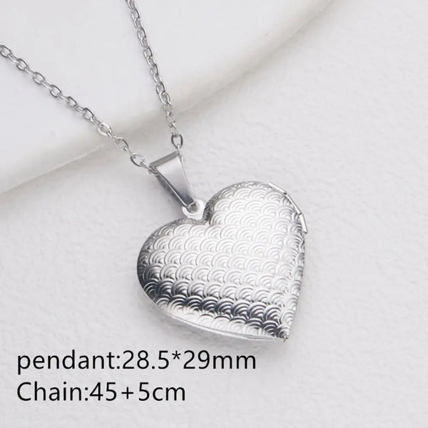 Silver heart pendant necklace with a chain, featuring a detailed wave pattern design.