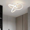 Modern clover-shaped LED ceiling light fixture with a white, swirling design mounted on a ceiling.