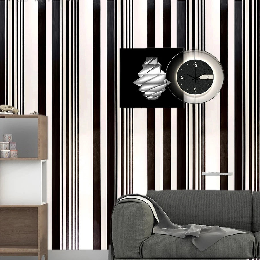 A close-up of black and white striped wallpaper featuring a round clock and a gray sofa.