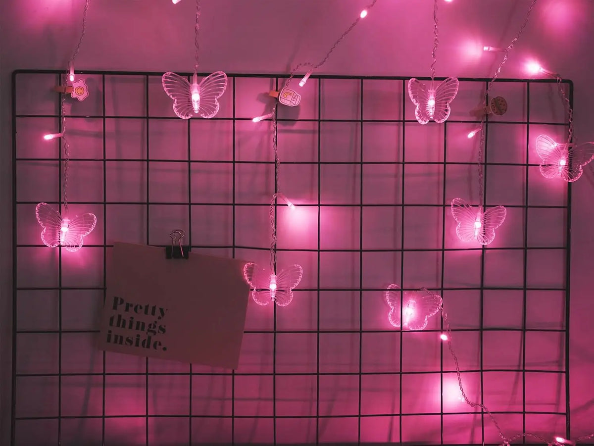Pink string lights illuminate a grid with glowing butterfly shapes.