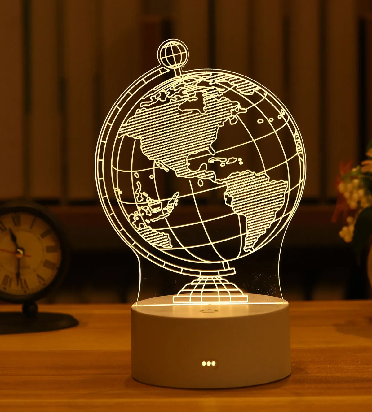 A glowing wireframe globe night light lamp rests on a wooden surface.