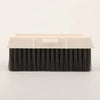A rectangular cleaning brush with black bristles and a white plastic handle for crevice cleaning.