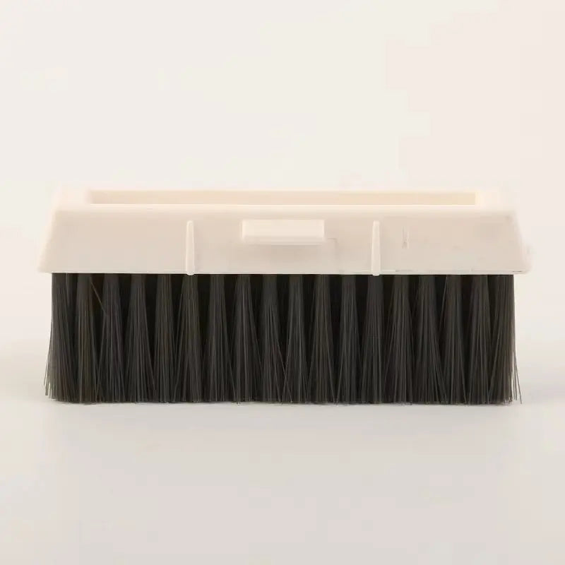 A rectangular cleaning brush with black bristles and a white plastic handle for crevice cleaning.