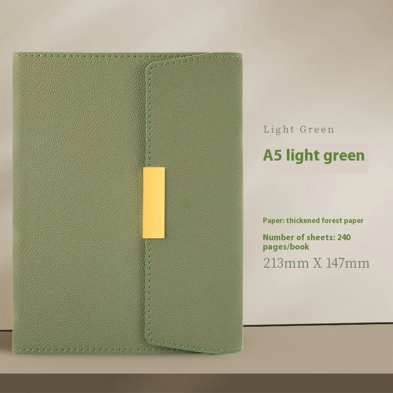 A light green A5 journal notebook with a gold-colored closure on a light brown background.