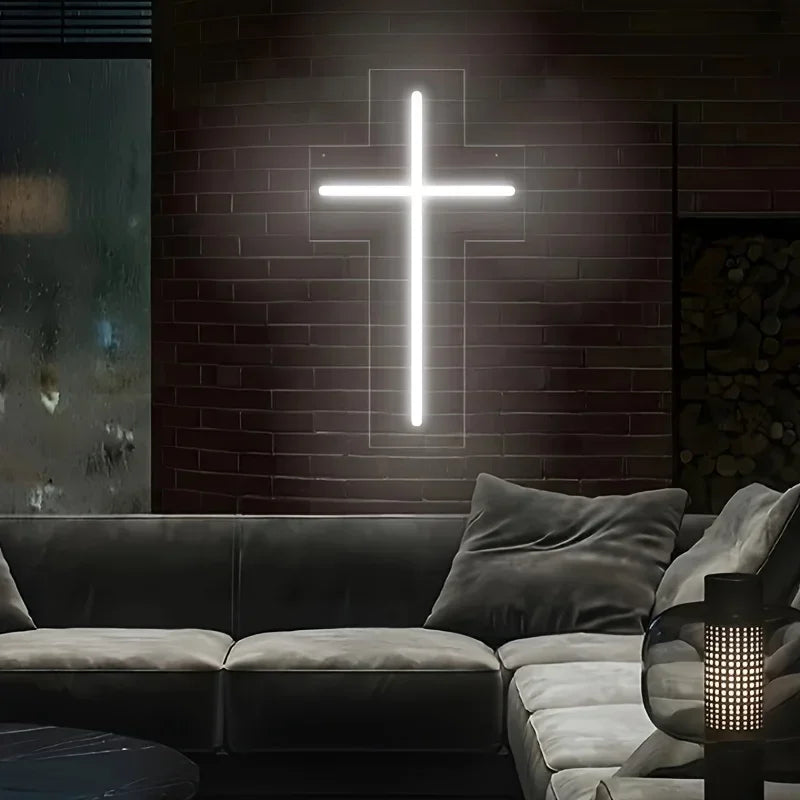A white neon cross sign is mounted on a brick wall above a modern sofa.
