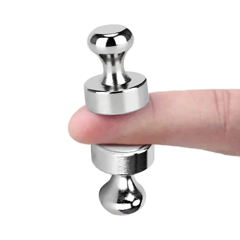A hand holds a silver neodymium magnetic pushpin, showing its size and shape.