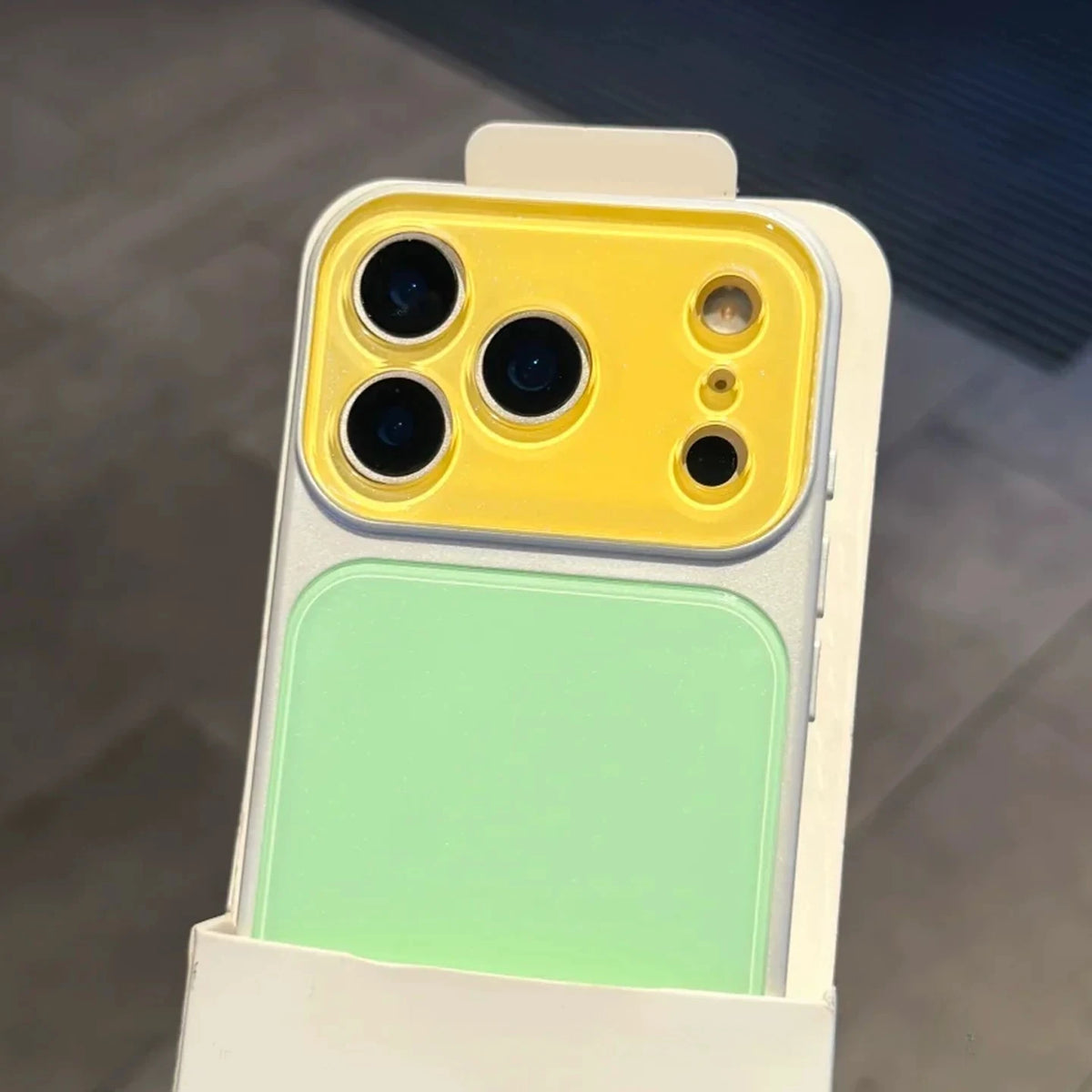 A color blocking shockproof phone case featuring a yellow camera window and a light green rectangular section.